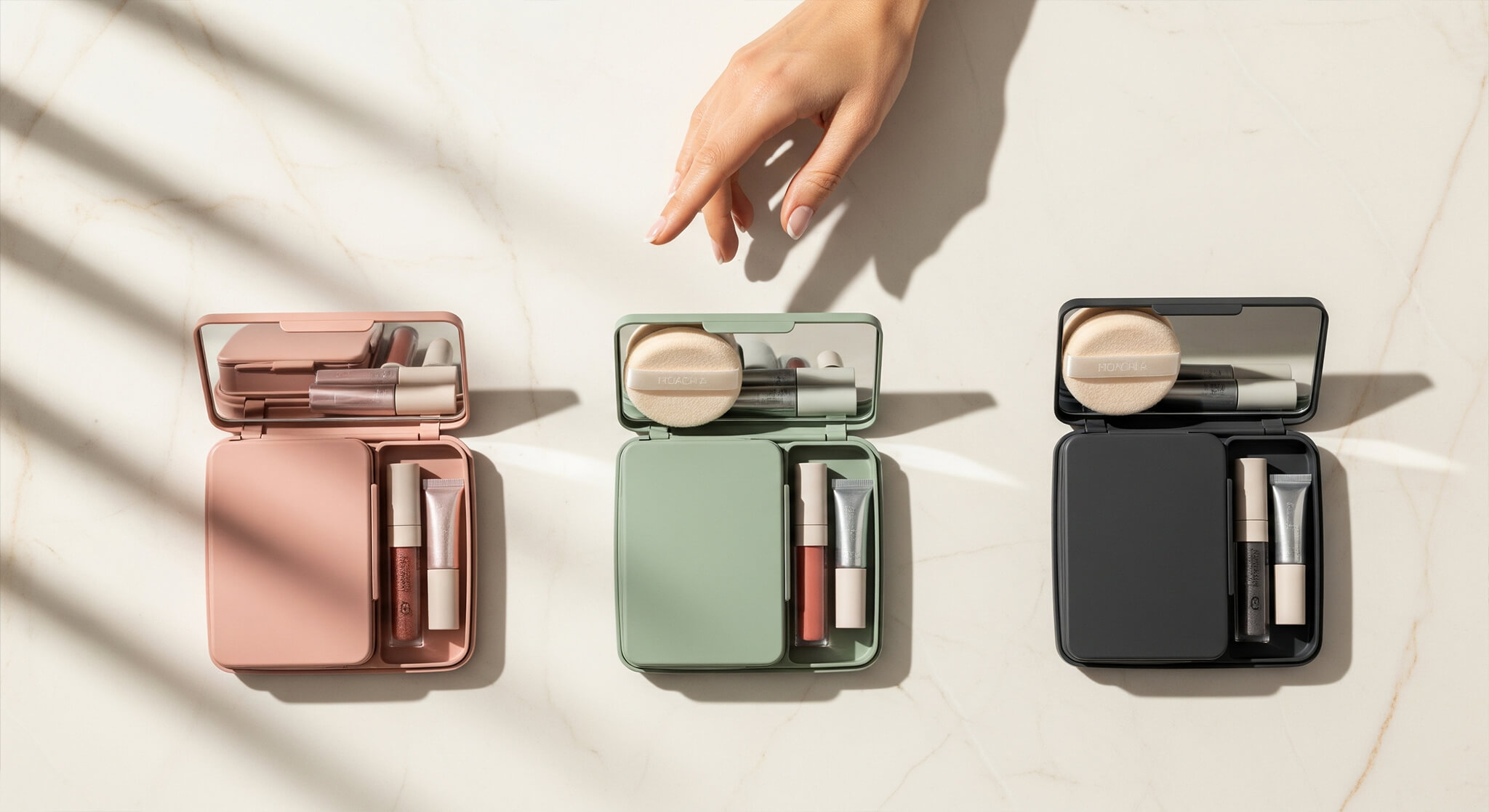image of three open makeup touch-up kits in dusty rose, sage green, and charcoal, arranged in a row on a cream-colored marble surface. Each kit contains a powder puff, a lip gloss, and other small items. A woman's hand is seen hovering over the kits, as if thoughtfully choosing one.