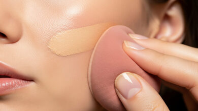 A guide on how to stop makeup from looking cakey and patchy, featuring a close-up of a hand using a pink beauty sponge to seamlessly blend foundation onto a cheek for a smooth, flawless finish.