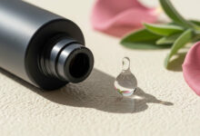 Alt Text: A close-up of a cosmetic bottle with a single clear droplet, representing hyaluronic acid, illustrating how makeup products containing this ingredient can hydrate mature skin, as discussed in the ultimate makeup guide for women over 35.