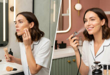 Split image comparing foundation application. Left: woman applying foundation with a sponge (cream/charcoal bathroom). Right: woman using an at-home airbrush makeup kit with flawless results (dusty rose/sage green bathroom), for beauty and makeup reviews