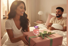 A gorgeous woman smiling as she presents a beautifully wrapped gift box with a celebrity fragrance (like Ariana Grande's) to a happy man in bed, addressing if such perfumes make good gifts.