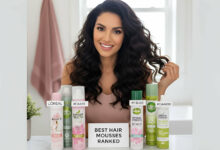 Ranking the best drugstore hair mousses: L'Oréal, Garnier, and Herbal Essences cans displayed on a stylish vanity, with a gorgeous woman showing off her voluminous hair.