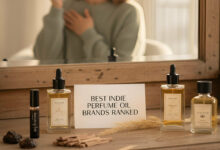 A reflection of a gorgeous woman applying perfume oil in a mirror, surrounded by various indie perfume oil brands and a "BEST INDIE PERFUME OIL BRANDS RANKED" sign, highlighting longevity.