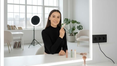 A confident woman applies contour makeup in a bright, modern room, as if filming a tutorial.