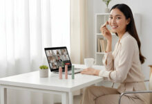 A confident woman at her modern home office desk applies quick makeup from a 5-minute kit before an online meeting.