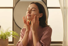 A serene woman applying face cream in a sunlit room, following a 3-step skin prep guide to protect her skin from the effects of daylight savings 2025.