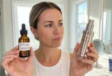 A woman skeptically comparing a bottle labeled "$15.00 SERUM" against a high-end luxury skincare bottle in a bright bathroom, illustrating a budget versus luxury product comparison